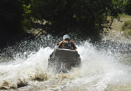 ATV上的人横过一条溪流旅游者在跨国的地形上行走高清图片