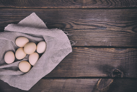 鲜鸡蛋在贝壳里躺毛灰纸巾上棕色木底右侧空位自由图片