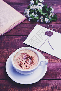 折后再开抢喝棕色桌上的热咖啡卡布奇诺藏在一本开着的书和束白花后背景