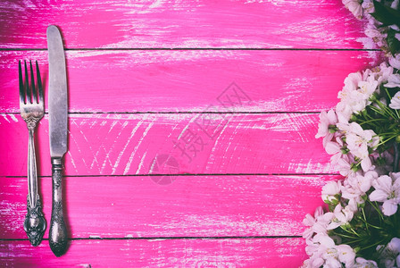 中间空的粉红色木背景的铁叉和刀图片