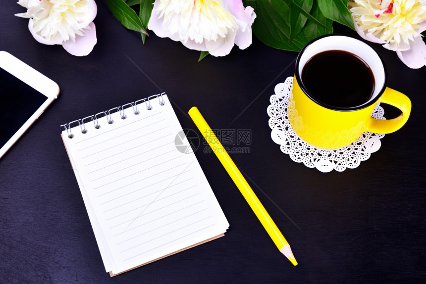 清空笔记本和黄杯黑底顶视图上含咖啡的清空笔记本和黄杯图片