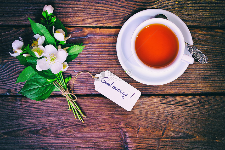 一杯茶和束盛开的茉莉花束上面贴有纸标签早上好刻着顶层风景图片