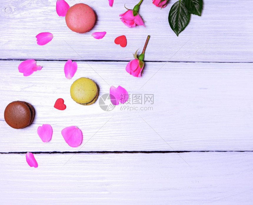白木底的玫瑰花瓣和马卡龙图片