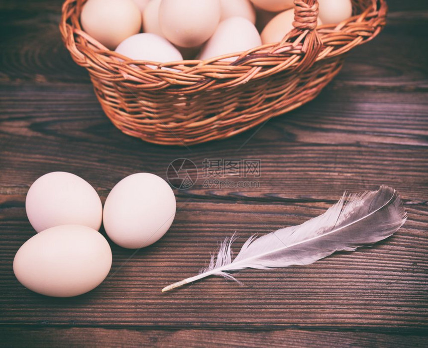 近视图竹篮里的鸡蛋和桌上的羽毛图片
