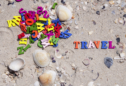 字词旅行由海滨上带有贝壳顶视图的小型多彩木字母组成图片