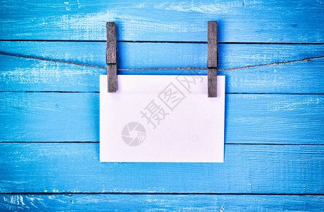 白纸信封挂在一根绳子上系着蓝色背景的木制旧衣帽图片