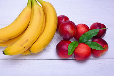 白色木制背景的黄香蕉和红桃图片