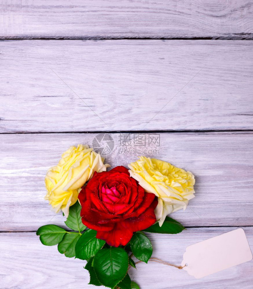 三朵花玫瑰和一张白纸标签挂在木背景上顶部空间图片