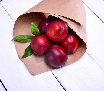 红色桃子在白木桌纸袋中的熟红桃子背景