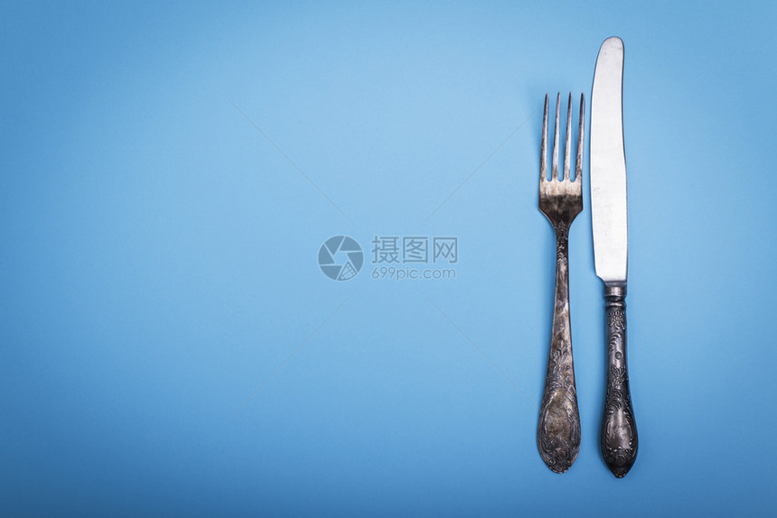 蓝色背景的旧铁叉和刀左边空最高视图图片