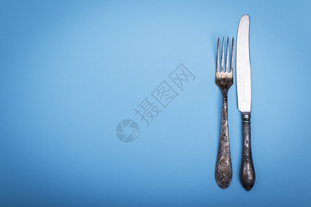 蓝色背景的旧铁叉和刀左边空最高视图背景图片