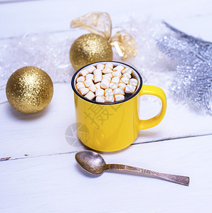 黄色杯子里有棉花糖的热巧克力白木本底有圣诞玩具图片