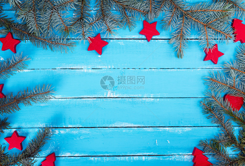配有绿色采树枝和圣诞装饰品的平行板蓝色木背景中间空图片