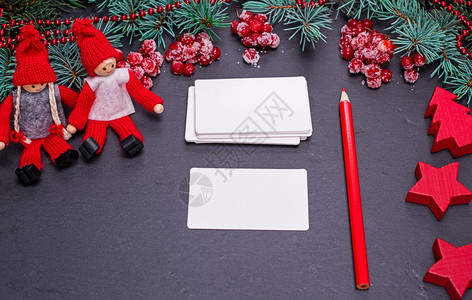 黑色背景的白纸名片和圣诞装饰品中的红铅笔最高视图图片