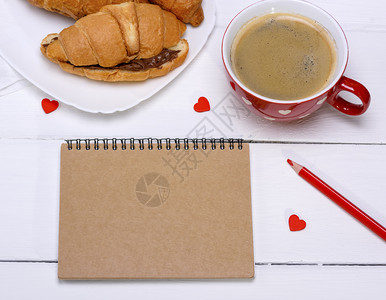 纸面笔记本上有棕页红色杯子白桌上有咖啡最视图图片