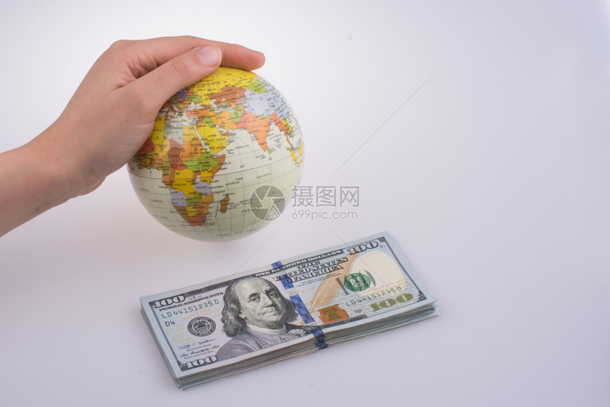 人类手拿着一个模型地球站在白底面的美元钞票旁边图片