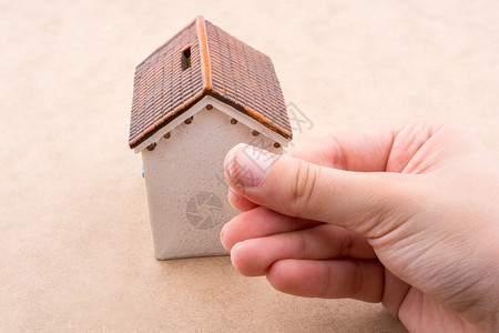 小模特儿房子和手浅棕色背景的手背景图片