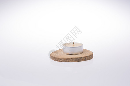 在白色背景的一块木头上放置的蜡烛高清图片