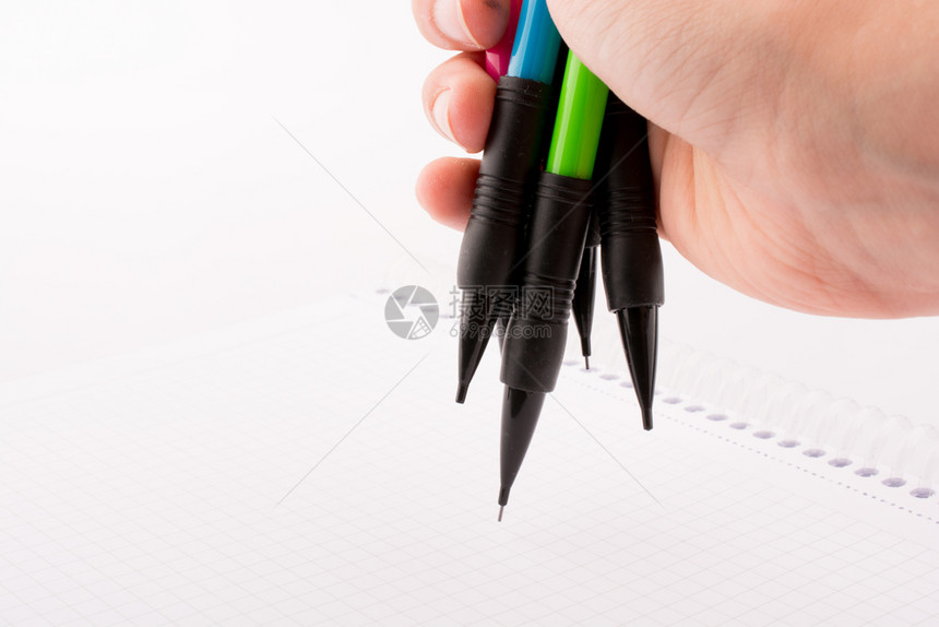 白色背景上手持不同颜色的机械铅笔图片