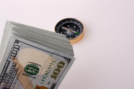 白背景指南针旁的美元钞票背景图片