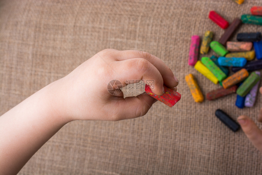 用过的彩色蜡笔和一只手握着的幼儿手图片