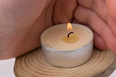 手保护在木头上放置的燃烧蜡烛背景图片