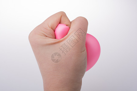 用白色背景的手挤压粉红色气球图片