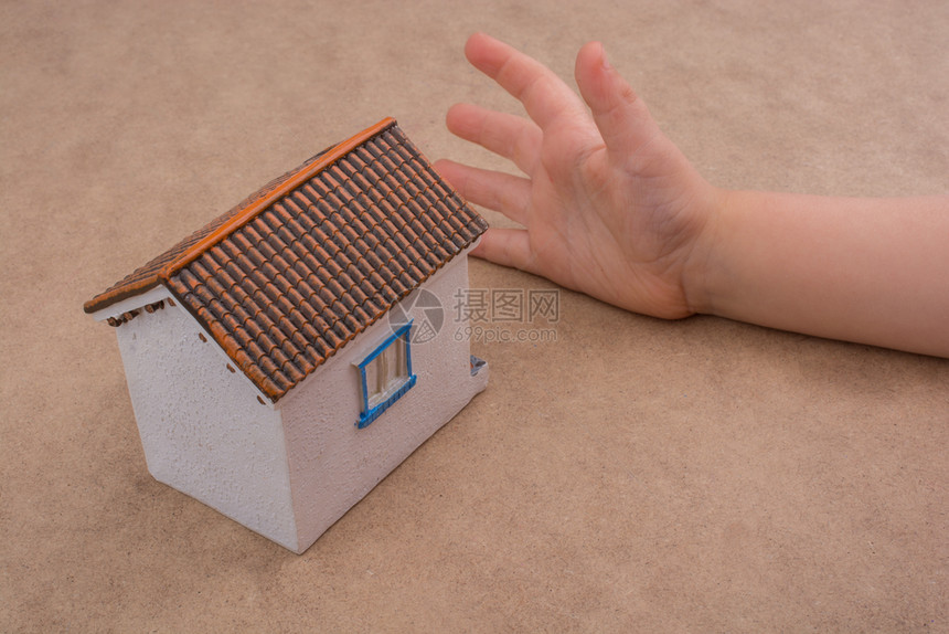 小模特儿房子和手浅棕色背景的手图片