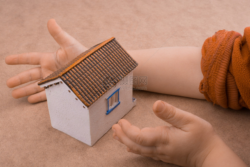 小模特儿房子和手浅棕色背景的手图片