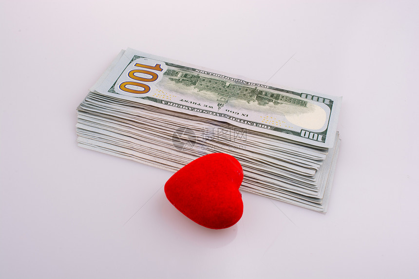 白底红色心形物体旁边的美元钞票图片