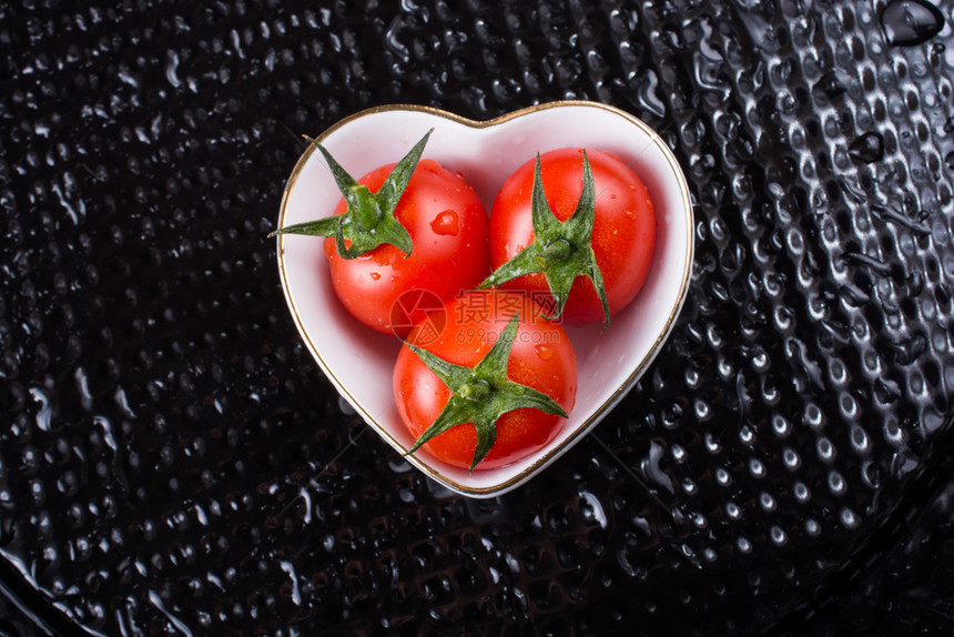 红熟樱桃番茄在心形碗中的番茄图片