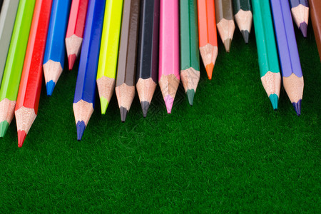 青草上的彩色笔人工草上的彩色铅笔背景图片
