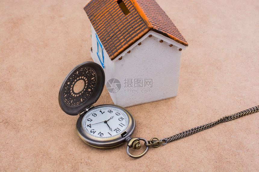 小模范房子和手表挂在棕色背景的小模范房子图片
