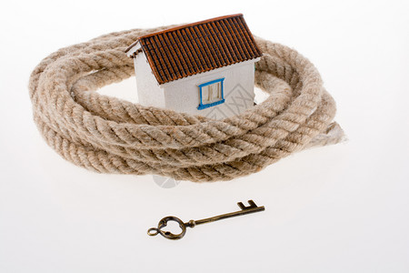 被绳子环绕的钥匙和房屋被白色背景的绳子环绕背景图片