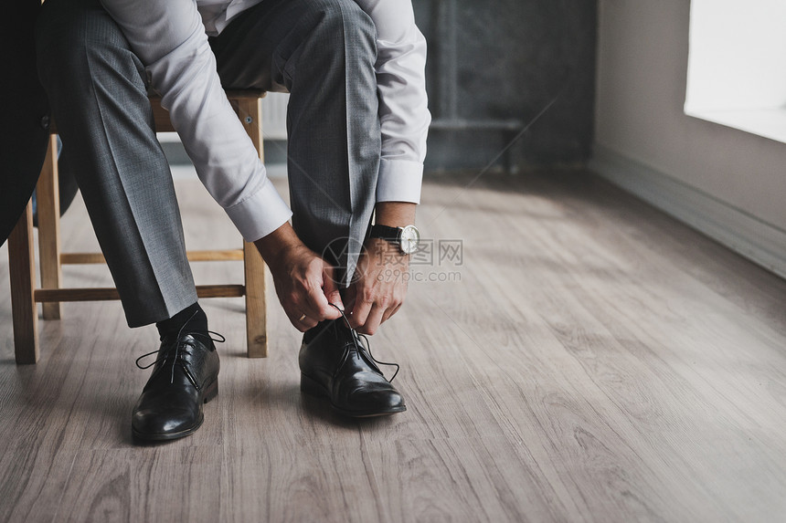 穿商务西装的男人绑着鞋带把你的绑在子上过程图片