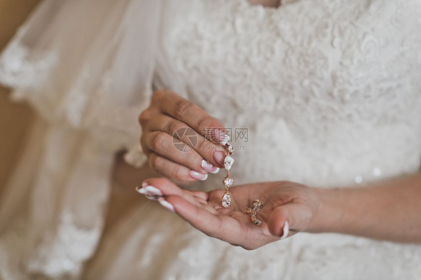 新娘展示了握在手掌上的耳环女手握着美丽的502件装饰物的重量图片