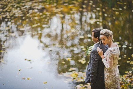 一对夫妇在秋湖岸边拍婚纱照图片