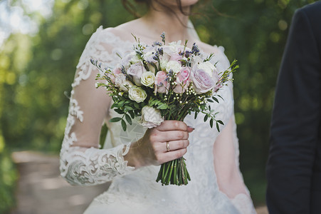 新娘手里拿着一束鲜花手柄脆弱新娘手里拿着一束美丽的花沿着绿地走来去图片