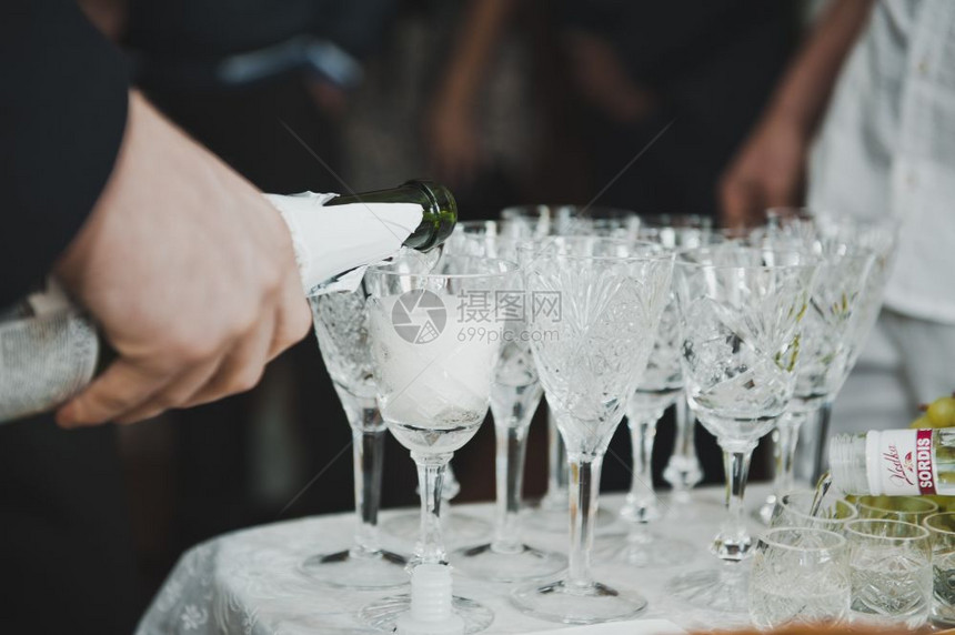 用酒装杯子的过程年轻人往杯子里倒香槟年轻人把香槟倒进玻璃杯里图片