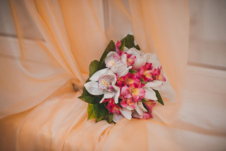 新娘的花束躺在窗帘上的橙色图片