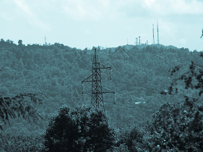 高电压输线路有选择地关注电杆视广播和移动天线在背景山丘上飞行冷锥形图片