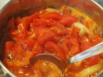 番茄汤准备番茄汤的制备在带勺子的煤气灶上的酱锅中煮沸图片