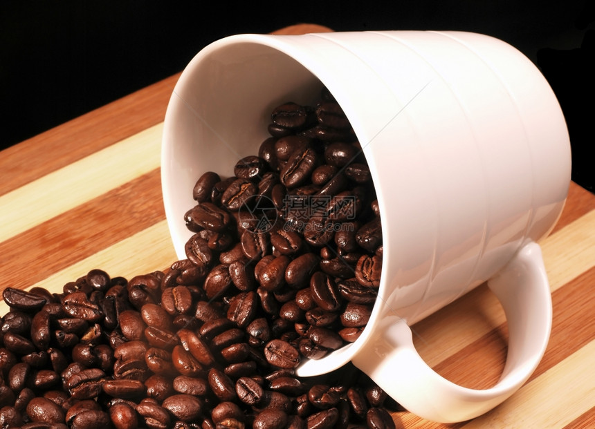 杯子上的咖啡豆洒在木板上图片