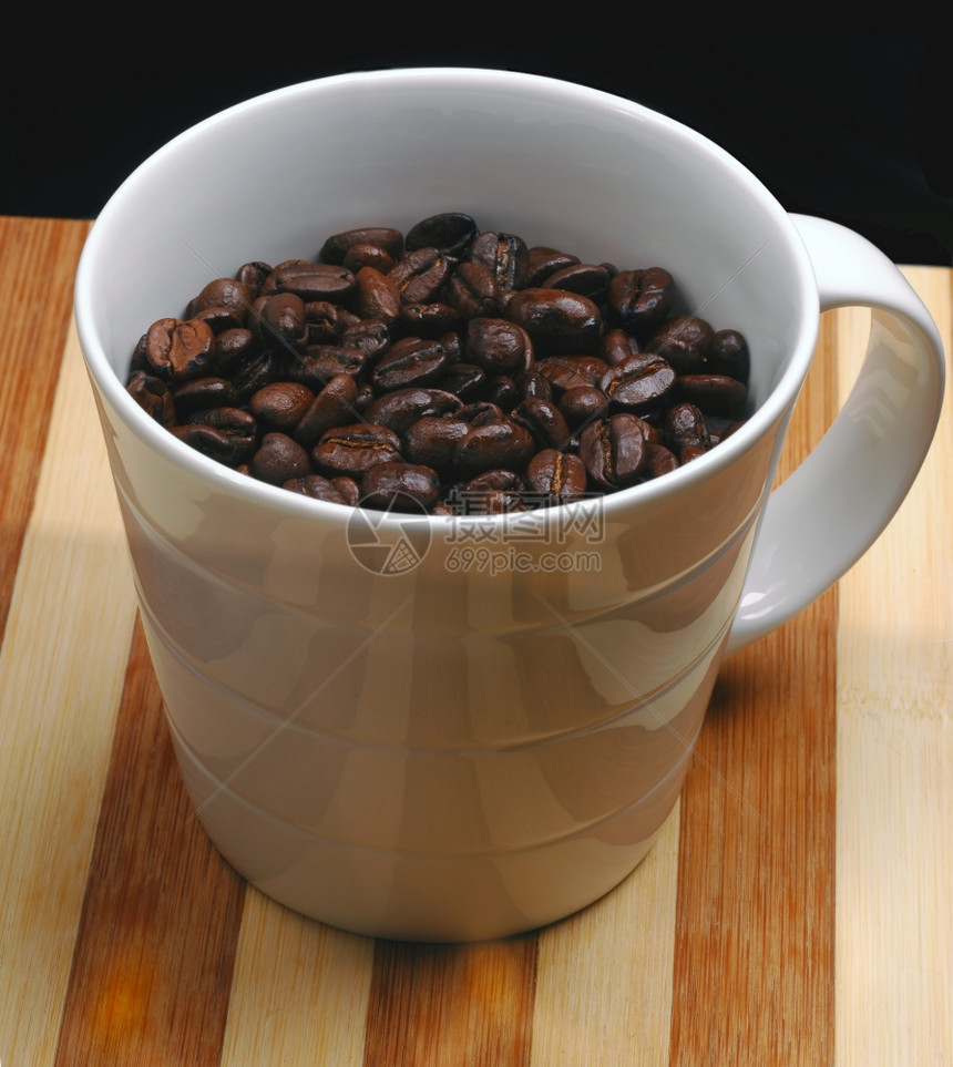 木板上一个杯子的咖啡豆图片