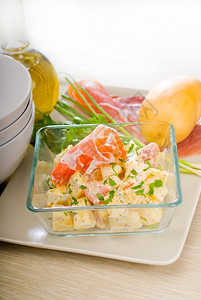 新鲜家庭制的马铃薯和火腿沙拉配有原料碗和餐具放在桌上图片