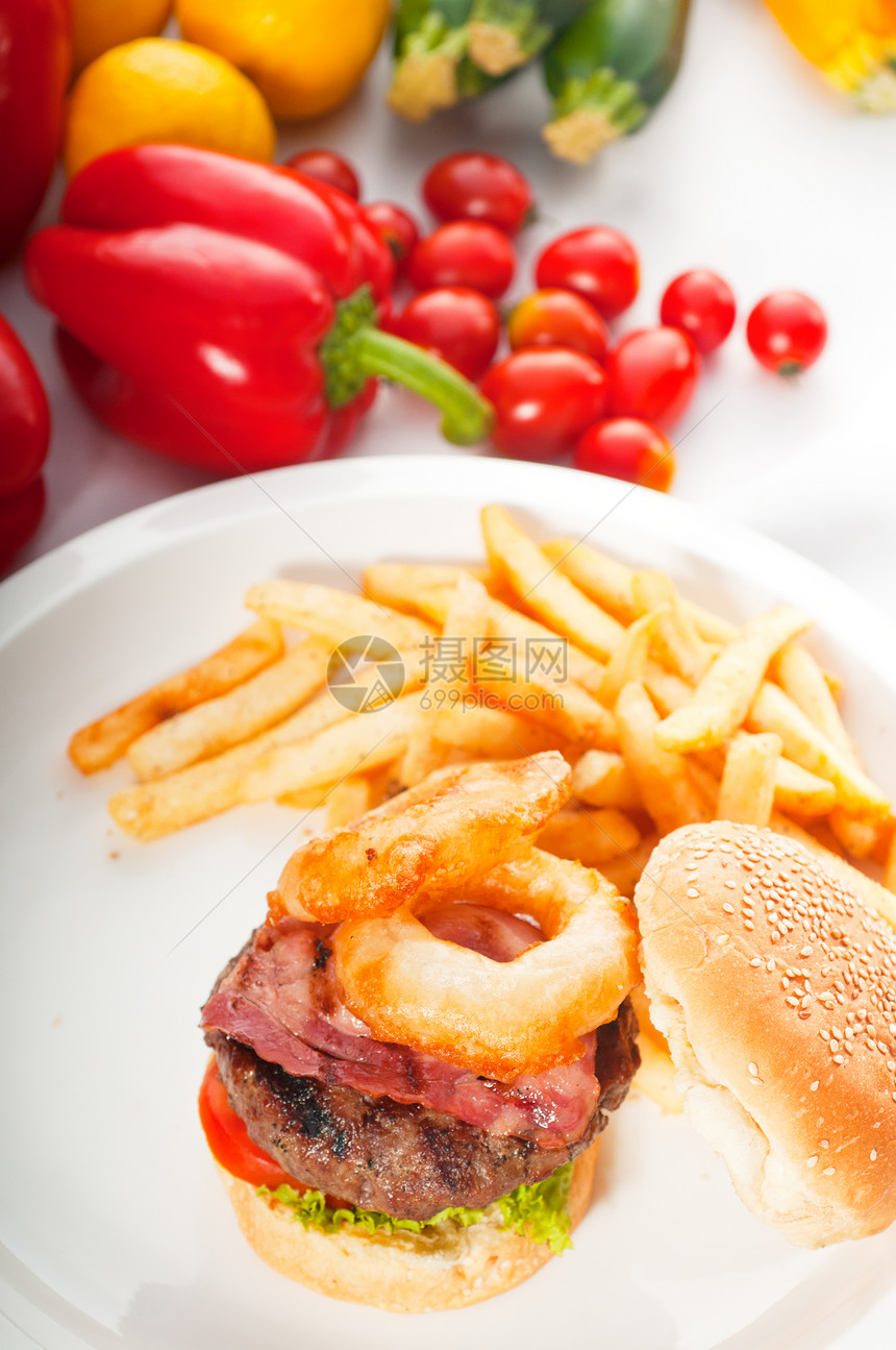 美国经典汉堡三明治配洋葱环和薯条背景有新鲜蔬菜在PORTOFOLIO上更美味的食品图片