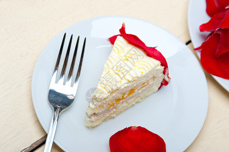 花瓣蛋糕带红玫瑰花瓣的奶油芒果蛋糕背景