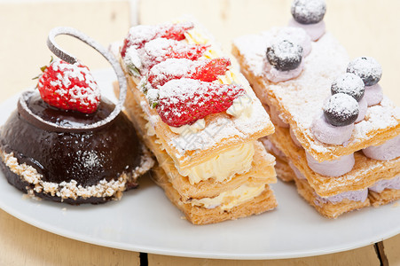 选择新鲜奶油拿破仑和巧克力慕斯蛋糕甜板背景图片