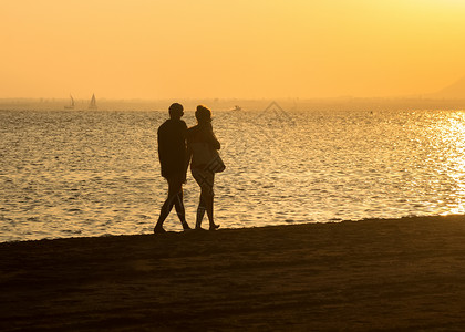 日落情侣在海滩上浪漫步图片