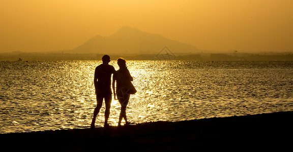 日落情侣在海滩上浪漫步图片
